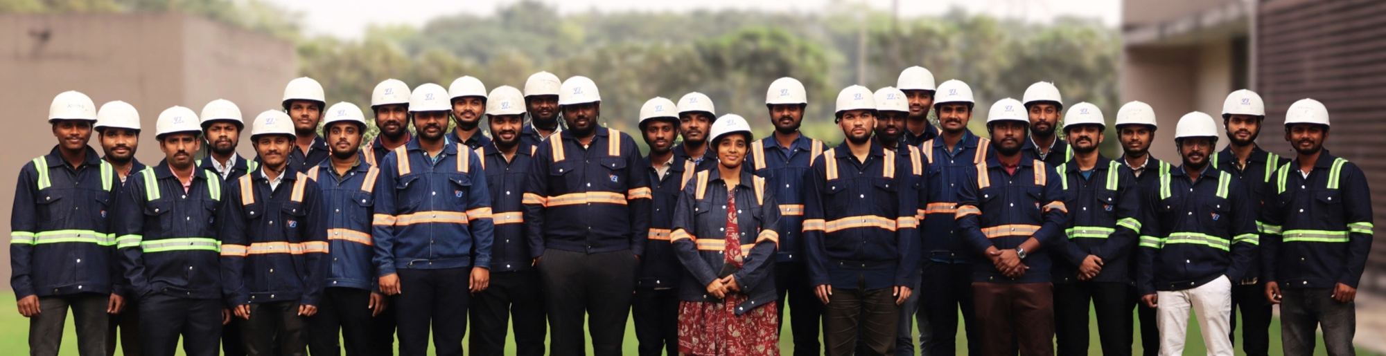 The VB Engineering team in coveralls and hard hats standing together on a plant lawn