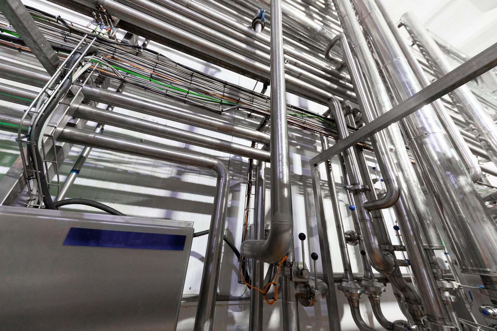 Overhead stainless steel pipe runs crossing a process hall