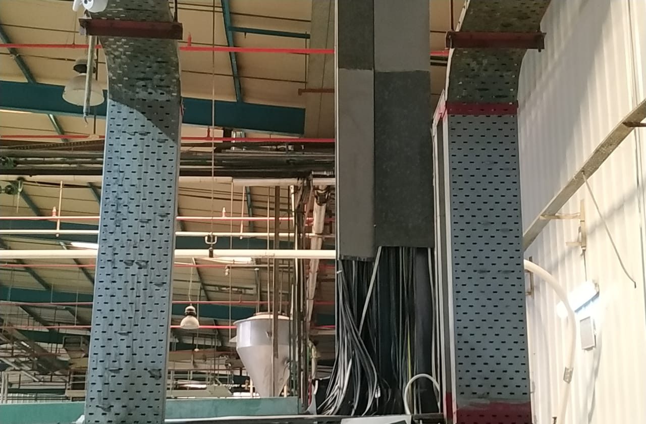 Multi-tier cable trays rising through a Gulf process plant building, carrying power and control cables to switchgear below