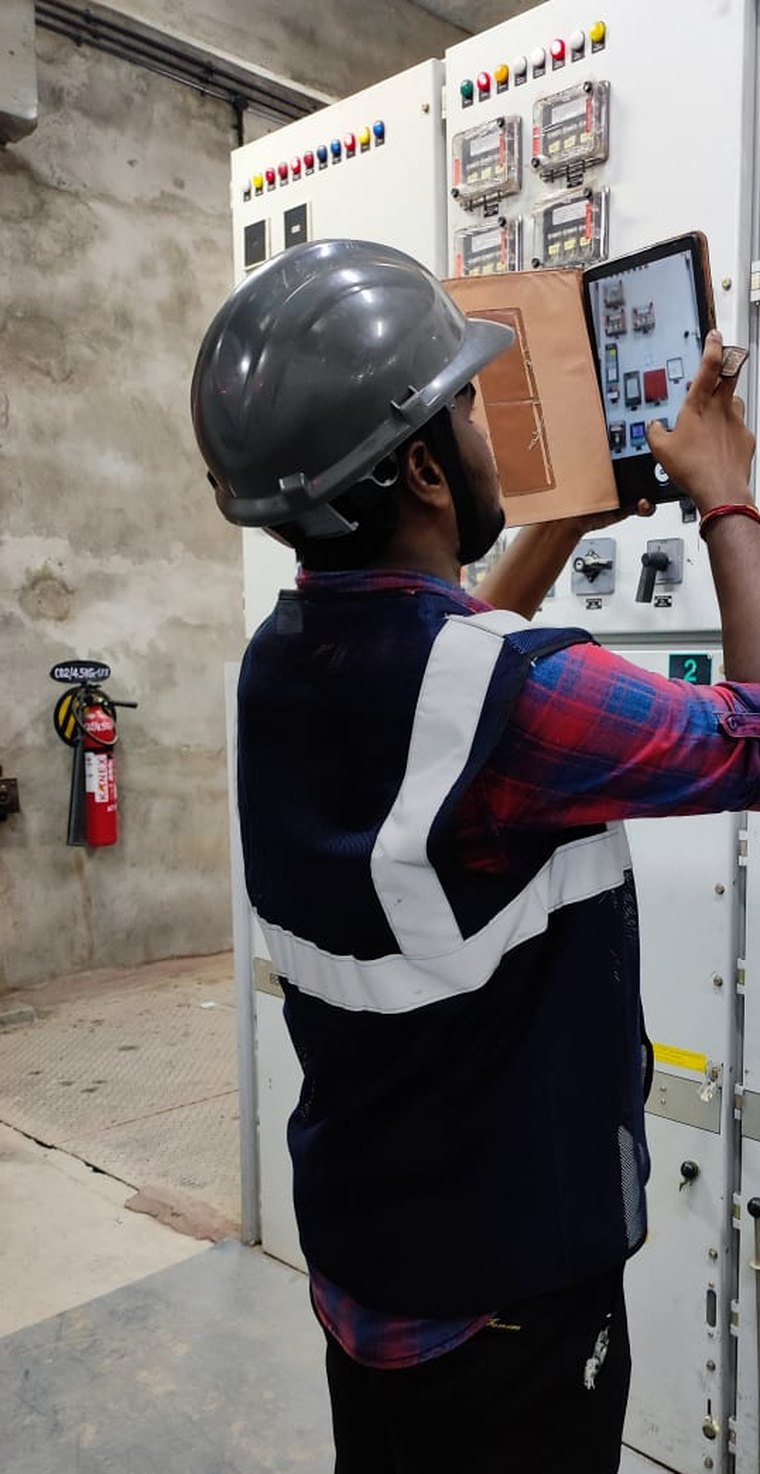 VB engineer capturing switchgear nameplate and settings data on a tablet, cubicle by cubicle, on an arc flash study walkdown